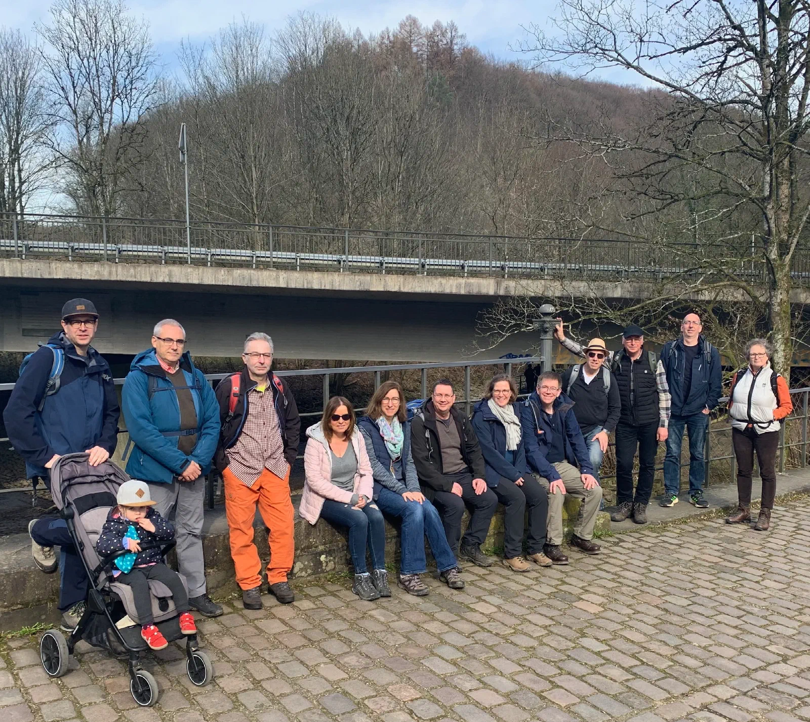 Die Wandergruppe sitzt für ein Gruppenfoto auf einer Mauer
