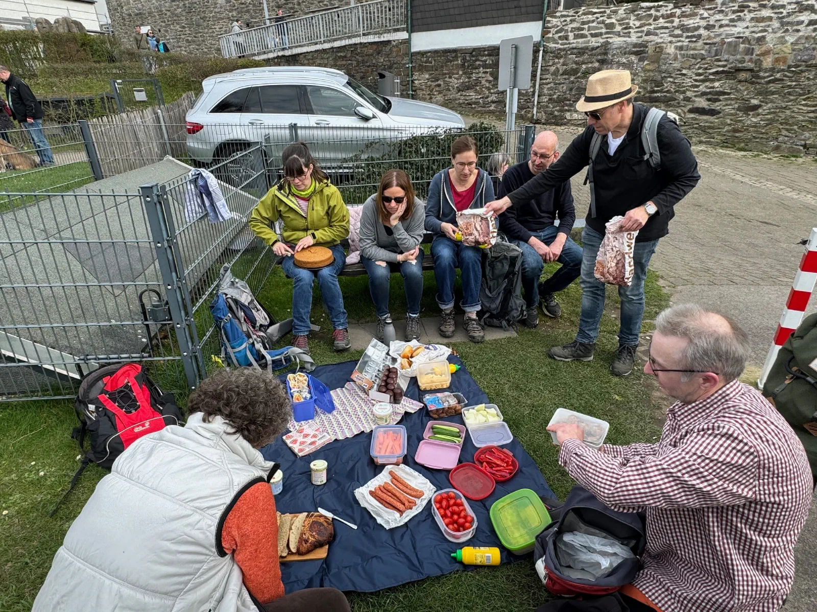 Teilnehmer sitzen und stehen beim Picknick auf einer Decke