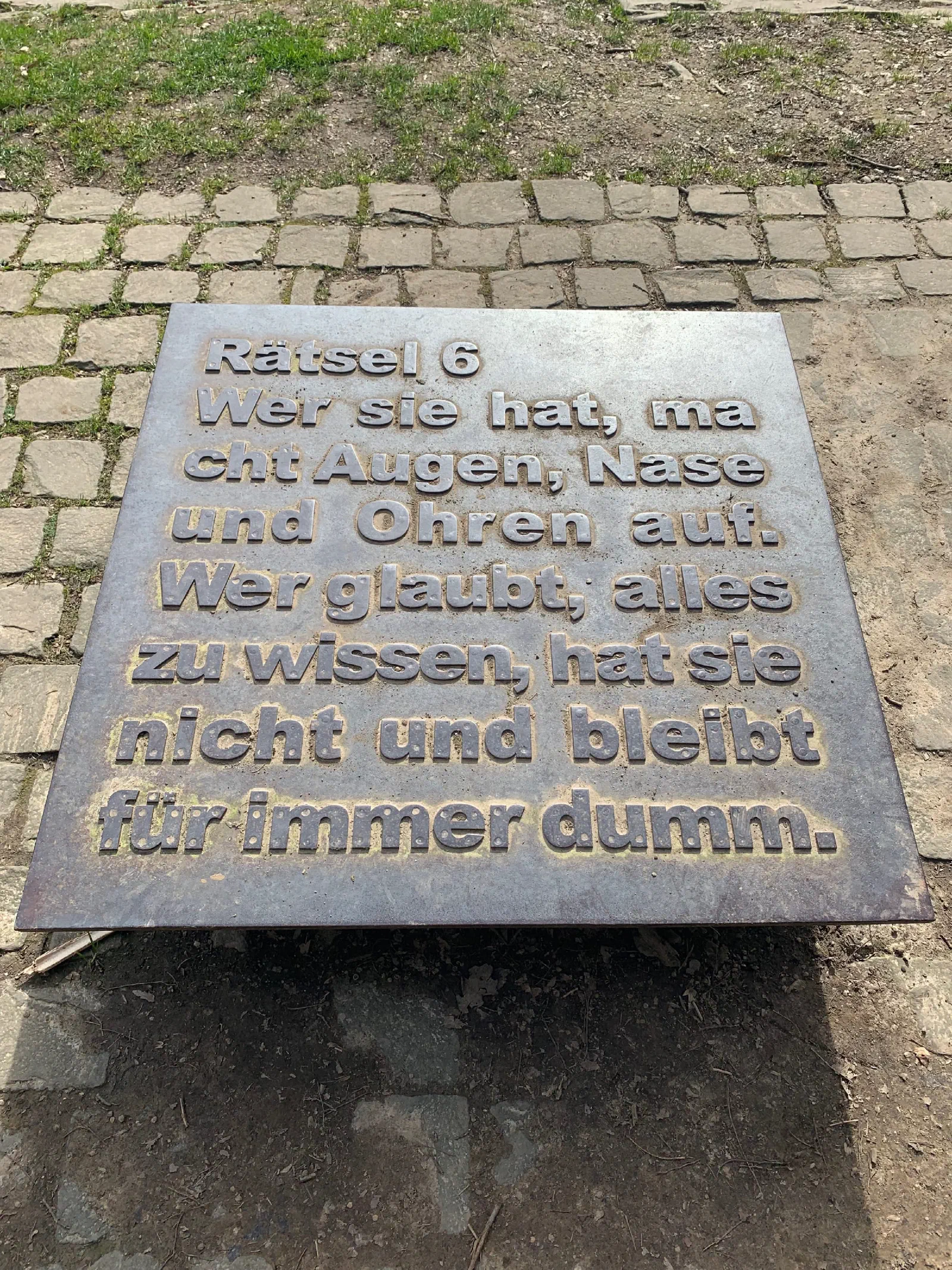 Metalltafel im Boden mit dem Rätsel Nummer 6