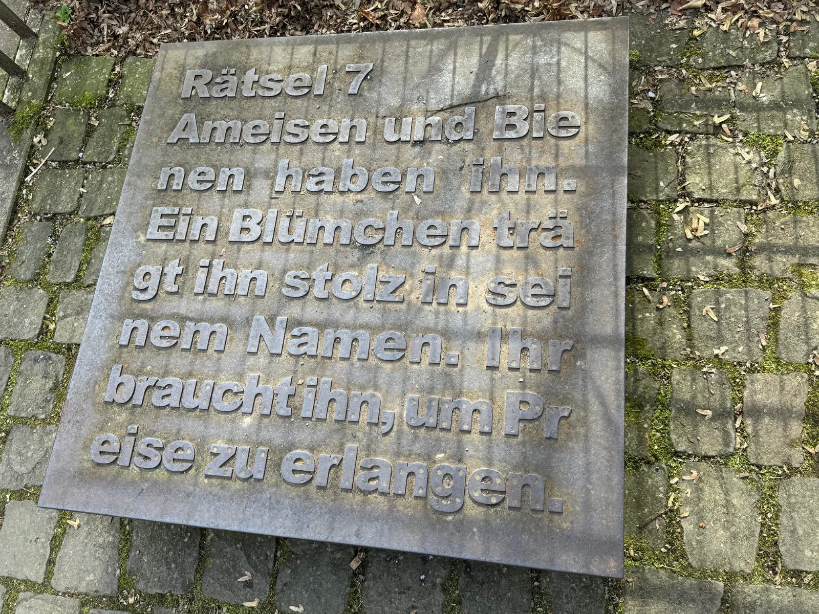 Metalltafel im Boden mit dem Rätsel Nummer 7