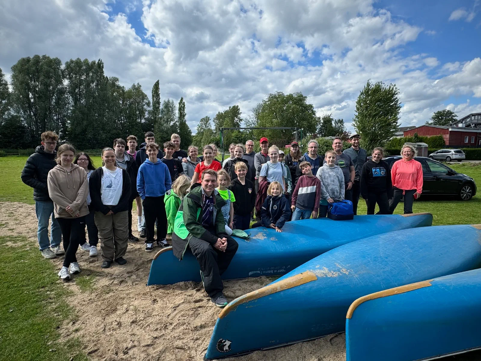 Gruppenfoto aller Teilnehmer vor blauen Kanus am Ufer
