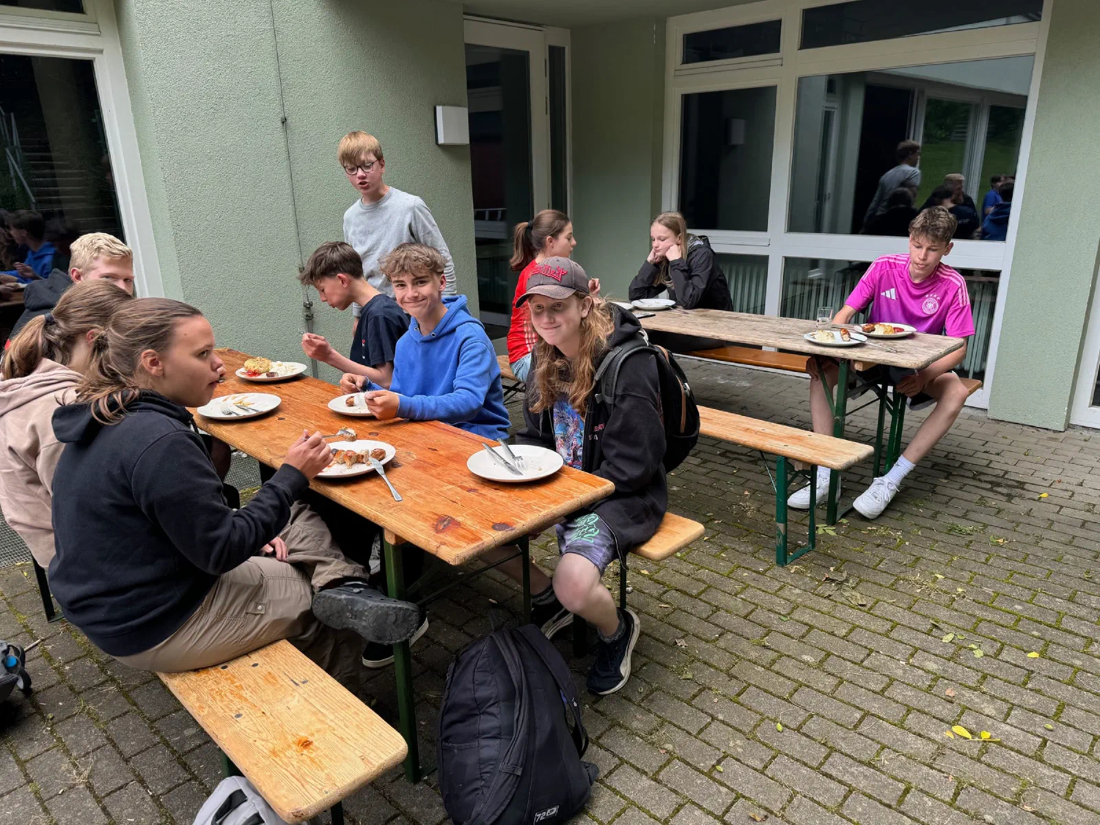 Teilnehmer essen an Bierbänken vor dem Vereinshaus